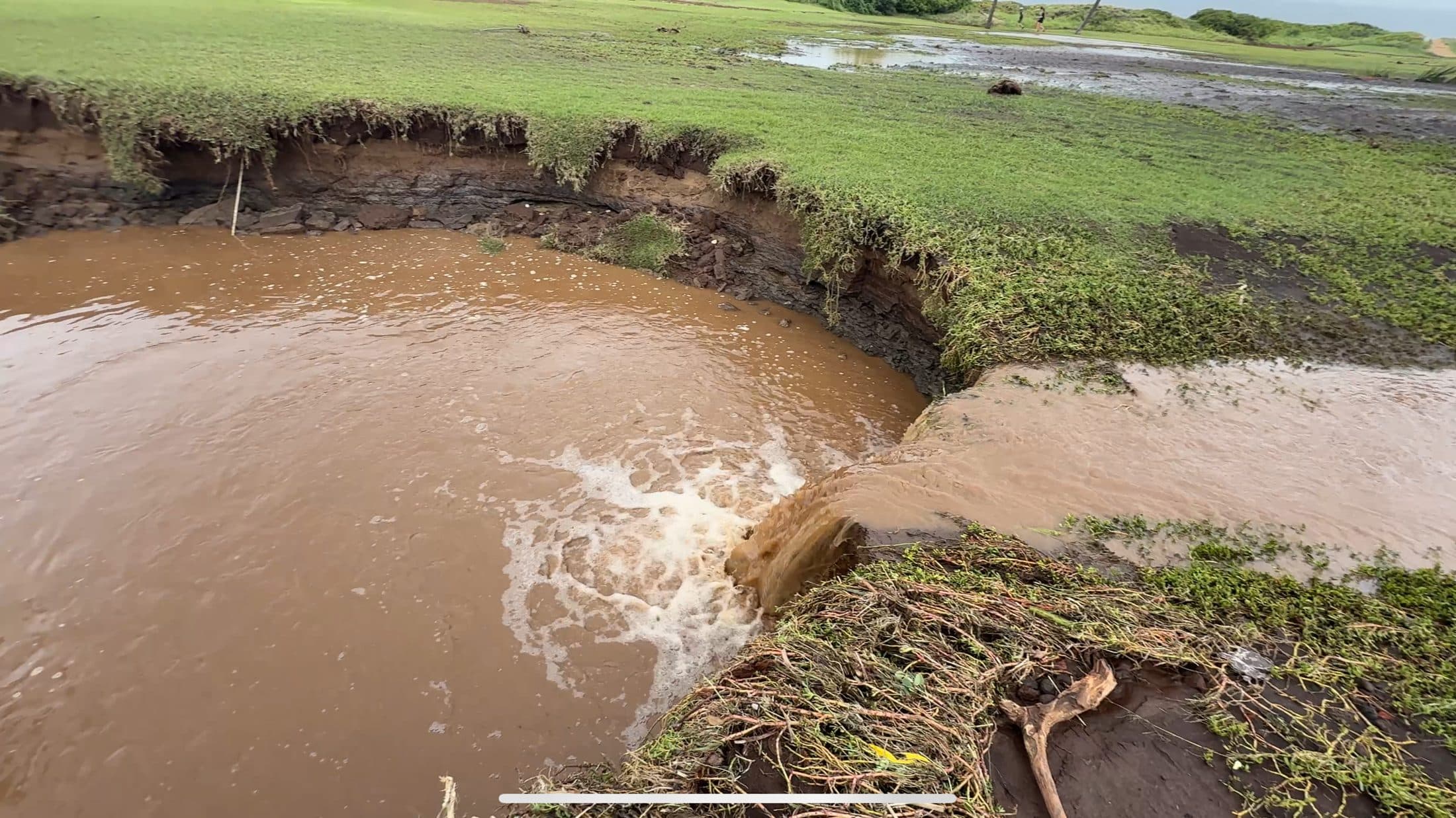 Brown floodwater flowing through the newly opened channel